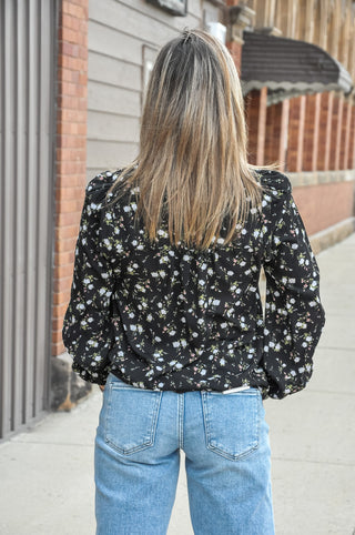 A delicate all-over print of cream and white roses on a rich black ground is framed by a frilled split V-neckline for a feminine, editorial touch that instantly elevates the look.