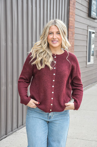Designed in a beautiful Burgundy shade, this soft solid sweater features a classic crew neckline, long sleeves, and button-front detailing for a timeless, polished look.