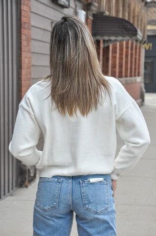 An adorable dog in a sporty sweater adds spirited charm, while the relaxed oversized fit keeps it easy to throw on and go.