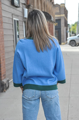 The soft blue body contrasts beautifully against forest green ribbed trim at the crew neckline, cuffs, and hem for a polished, sporty-chic look. 