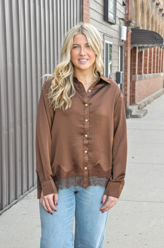 This satin loose fit shirt from Anniewear features a delicate lace hem detail that peeks out from under the silky fabric.