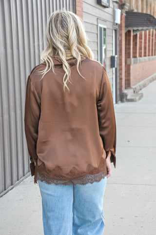 This satin loose fit shirt from Anniewear features a delicate lace hem detail that peeks out from under the silky fabric.