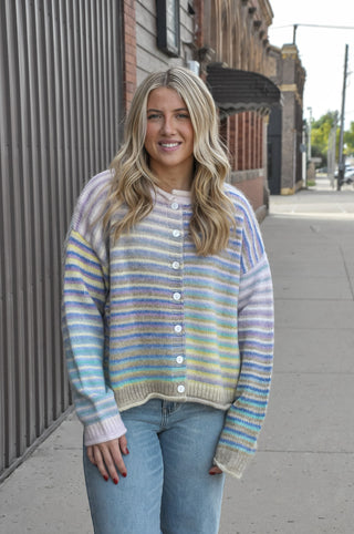  The fuzzy acrylic-poly knit has a plush, cozy feel that's as comfortable as it is eye-catching, while the horizontal multicolor stripes and full button-down front give it a playful, vintage-inspired charm. 