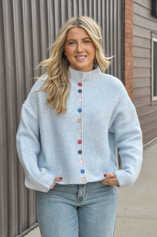 Bright, cheerful, and full of personality, the Stand Color Sweater Cardigan with Colorful Buttons is the perfect way to add a playful touch to your wardrobe. 