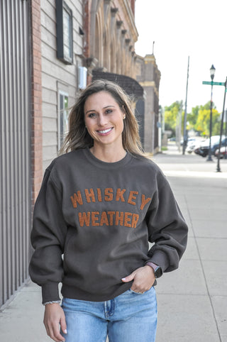 This cozy crewneck features bold "WHISKEY WEATHER" text in camel embroidery for a warm, textured look that's equal parts stylish and spirited.